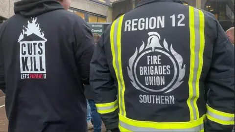 A close-up of the backs of two men wearing tops that say 'cuts kill'. 