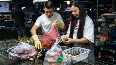 Vendors arrange bags of seafood at a seafood market in Beijing. 