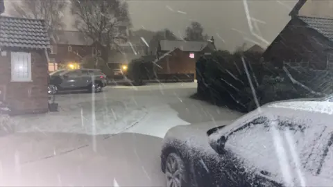 BBC Snow on a street and covering a car on a driveway