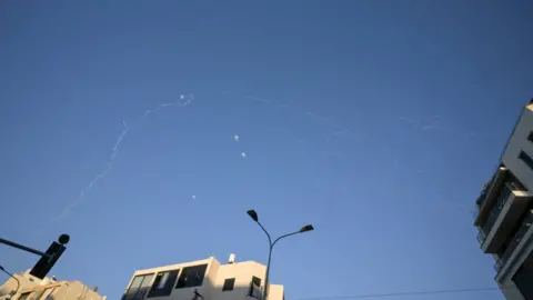 Reuters Vapour trials are seen in the sky above Tel Aviv, Israel, after the interception of projectiles launched from Lebanon (9 March 2026)