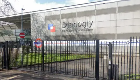 Google Streetview image of Djanogly Academy, a modern steel and glass building by a busy road