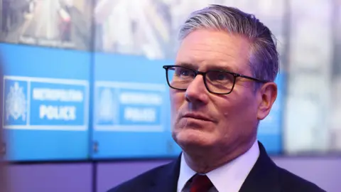 PA Media The UK Prime Minister Keir Starmer wearing black glasses and a suit positioned to the right of the frame looking up towards the left.