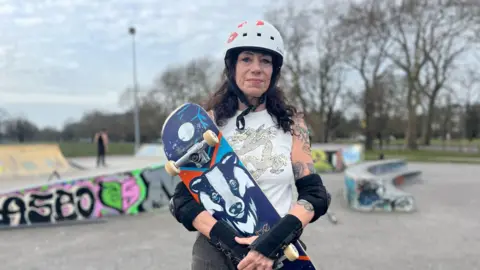 Jules Kurzeja, 64, hold her skateboard in at a skate park in Clapham.