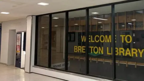 SHARIQUA AHMED/BBC Sign reads 'Welcome to Bretton Library' in yellow text between glass window 