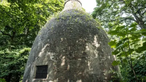 Historic England The bottle-shaped brick building in Swinton is surrounded by woodland