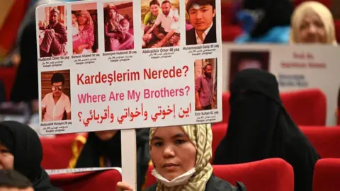 Getty Images A Uyghur Muslim woman holds a sign with pictures of her brother and the words: Where are my brothers?