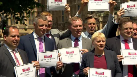 Chris Bryant and other LGBT Labour MPs opposing the DUP deal with the Conservatives in 2017, holding a sign saying 'Drop the DUP deal'