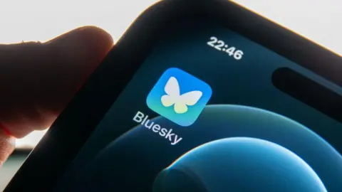 A person holding a phone with the Bluesky logo on it