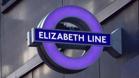 Getty Images The Elizabeth line roundel displayed on the side of a building, with a purple hollow circle and a blue rectangle across it with writing reading 'Elizabeth line'.