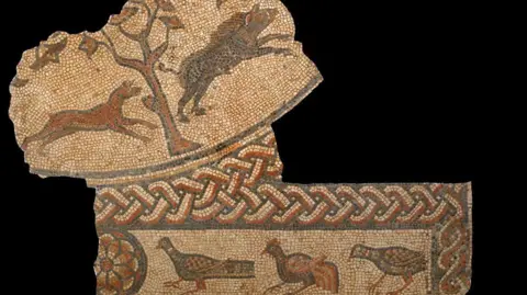 Fragment of a Roman mosaic showing a boar being chased by a hunting dog past a tree and a border showing three game birds