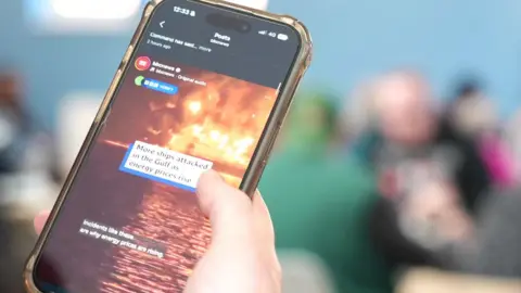 A mobile phone on the BBC News instagram page showing pictures of the war in Iran.