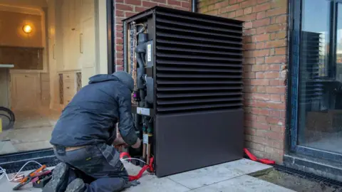 Getty Images Air source heat pump installers install a heat pump unit into a house near Ashford, UK, on 29 November 2024 