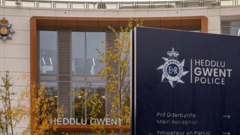 Headquarters of Gwent Police, with a blue sign reading Heddlu Gwent Police and a window behind