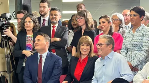 Wes Streeting, Rachel Reeves and Sir Keir Starmer sit next to each other, smiling broadly