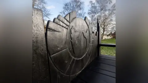 The Prodigy/Facebook A close-up image of the singer's devil-horned silhouette is carved into the dark-coloured wood of the bench's backrest