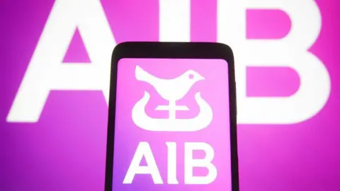 Getty Images AIB logo shown on a black phone. AIB text and logo is white and it is on a purple background. The AIB text is replicated behind the phone on another purple background.