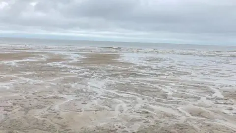 Sandy beach at Sutton on Sea with wavy sea in background