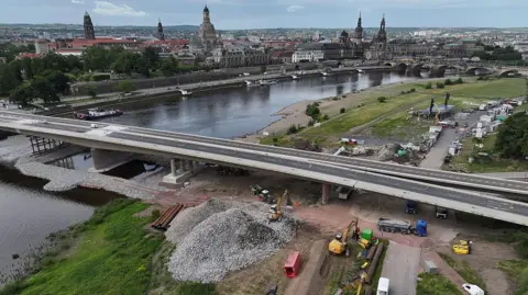 Bridge over the Elbe River under construction. In the background across the river is the city centre, including the Frauenkirche and other landmarks.