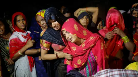 People mourn the deaths of relatives at a religious event in India, July 2024