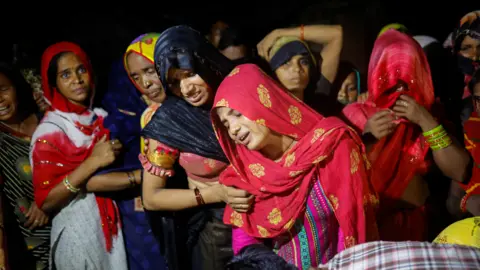 Reuters People mourn the death of a relative at a religious event in India, July 2024