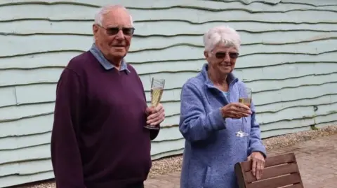 Simone Evans Christine and Peter Booker holding champagne glasses