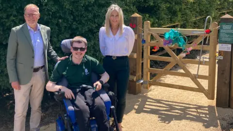 Councillor Paul Hodgkinson, National Star student Callum and Lynette Barrett, National Star Chief Executive, at the opening of the new accessible path at National Star College in Ullenwood