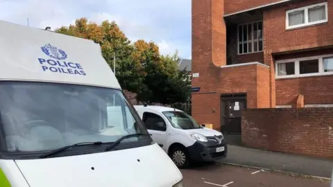 A white Police Scotland van parked outside a block of flats.