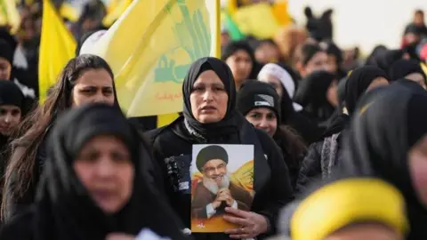 Reuters A woman holds a photo of the late chief of Hezbollah Hassan Nasrallah