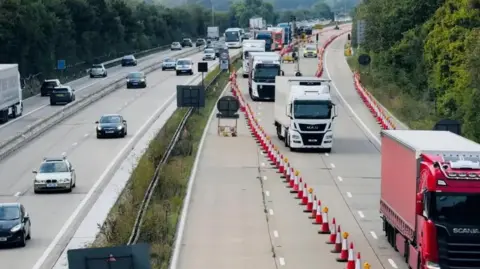 Lorries heading to Dover queuing on one side of the M20, herded by long rows of traffic cones  