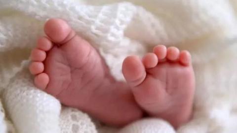 A baby's feet sticking out of a while blanket