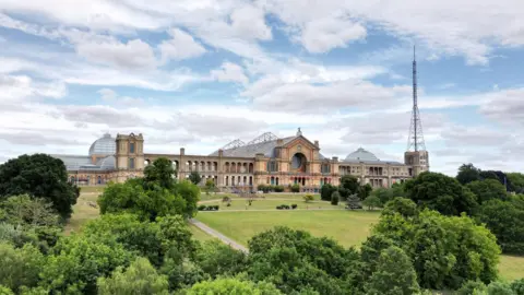 Getty Images A large palace-sized building on top of a hill surrounded by parkland and trees. There is a large TV transmitter on one side of the building. The sky is full of white clouds. 
