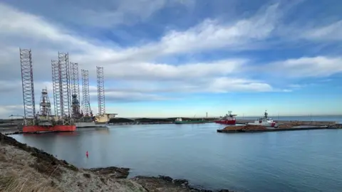A US Coast Guard ship is dwarfed by offshore industry infrastructure in Aberdeen harbour