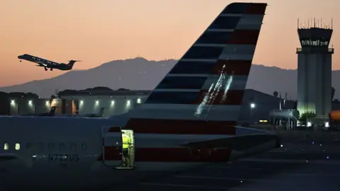 A plane takes off near the Hollywood Burbank Airport air traffic control tower at sunset