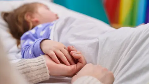 Getty Images Child in hospital bed with parent holding hand