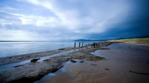 Getty Images Mudflats on the Solway coast in southern Scotland with water to the left and hills and grass to the right