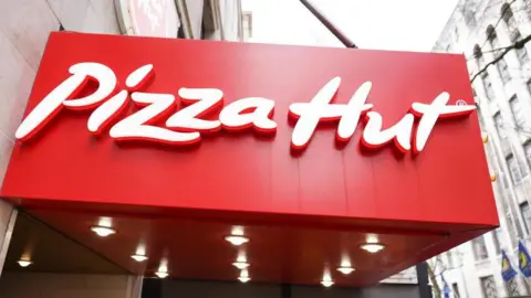 A bright red Pizza Hut logo on the side of a building 