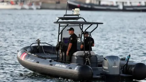 EPA Two uniformed naval guards in a boat patrolling a port area 