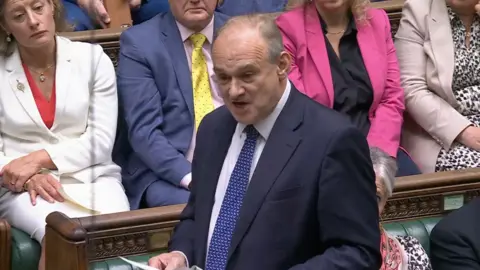 Ed Davey during PMQs wearing navy suit