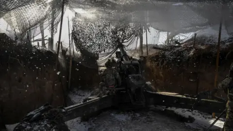 Reuters A Ukrainian soldier operating an artillery weapon from a trench in eastern Ukraine