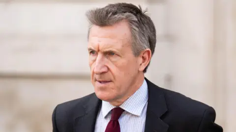 PA Media Dan Jarvis has grey hair and is wearing a dark red tie, black suit jacket and white and pale blue striped shirt.