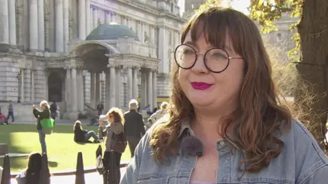 BBC Green Party councillor Áine Groogan standing in front of Belfast City Hall 