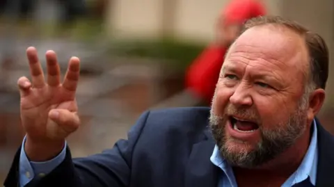 Reuters Conspiracy theorist Alex Jones gestures with his right hand as he is speaking with a defiant look on his face