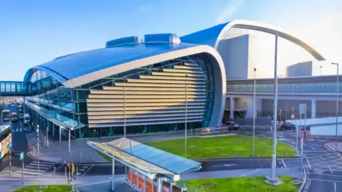 Outside of Dublin airport. The building has a glass front and a sweeping roof. 
