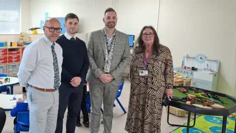 Hull City Council Three men and a woman, all smartly dressed, stand in a new special educational needs classroom at Dorchester Primary School in Hull. The bright, lightly coloured classroom includes play equipment, storage shelves and children's tables