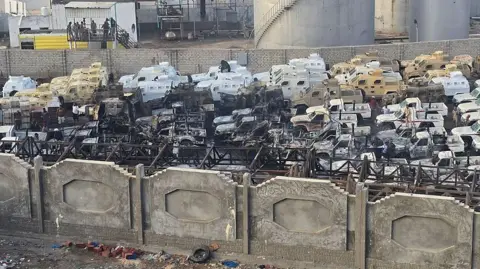 AFP Burned-out military vehicles and pick-up trucks following a Saudi-led coalition air strike on the port of Mukalla, southern Yemen (30 December 2025)