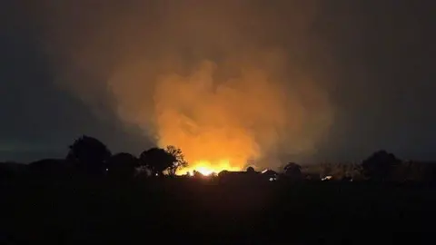 Jeremy Buxton/BBC An orange blaze in the distance with billowing clouds of smoke