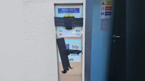 A pay machine with the payment slots covered by black tape