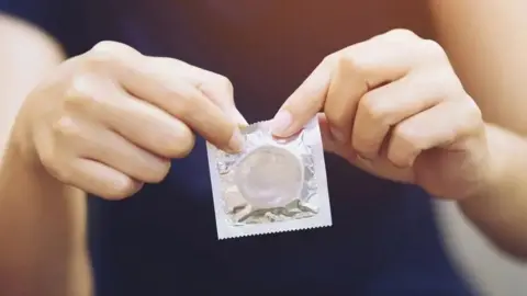 Close up of hands holding a condom. 