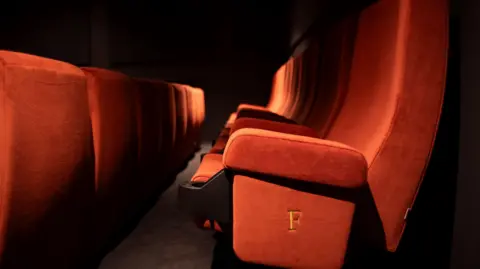 Kat Gollock Deep red cinema seating in rows, in close-up.