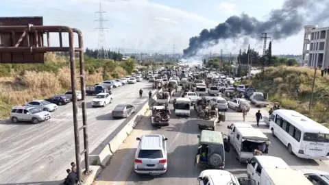 Smoke rises above a highway jammed with cars